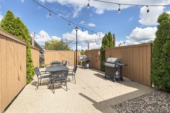 A backyard with a table and chairs and a grill.